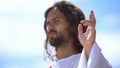 Preacher showing blessing sign against blue sky, hand of benediction, baptism