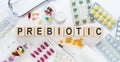 PREBIOTIC medicine word on wooden blocks on a desk. Medical concept with pills, vitamins, stethoscope and syringe on the