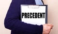 The PRECEDENT is written on a white sheet held by a man standing sideways