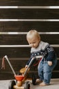 Precious Adorable Cute Little Blonde Baby Toddler Boy Kid Playing Outside on Wooden Toy Bicycle Scooter Mobile Smiling at the Came Royalty Free Stock Photo