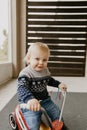Precious Adorable Cute Little Blonde Baby Toddler Boy Kid Playing Outside on Wooden Toy Bicycle Scooter Mobile Smiling at the Came Royalty Free Stock Photo