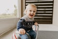 Precious Adorable Cute Little Blonde Baby Toddler Boy Kid Playing Outside on Wooden Toy Bicycle Scooter Mobile Smiling at the Came Royalty Free Stock Photo