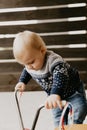 Precious Adorable Cute Little Blonde Baby Toddler Boy Kid Playing Outside on Wooden Toy Bicycle Scooter Mobile Smiling at the Came Royalty Free Stock Photo