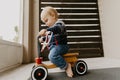 Precious Adorable Cute Little Blonde Baby Toddler Boy Kid Playing Outside on Wooden Toy Bicycle Scooter Mobile Smiling at the Came Royalty Free Stock Photo