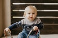 Precious Adorable Cute Little Blonde Baby Toddler Boy Kid Playing Outside on Wooden Toy Bicycle Scooter Mobile Smiling at the Came Royalty Free Stock Photo