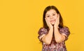 Precious face. Child pulls her cheeks up in affection. Girl cute smile on yellow background. Childhood and happiness