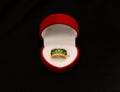 A precious golden ring with green stones in the heart-shaped box isolated on black background Royalty Free Stock Photo