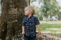 Precious Little Toddler Boy Dressed Up in the Outdoors Forest Park for Portraits in Autumn by Big Natural Tree Having Excited Fun Royalty Free Stock Photo