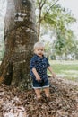 Precious Little Toddler Boy Dressed Up in the Outdoors Forest Park for Portraits in Autumn by Big Natural Tree Having Excited Fun Royalty Free Stock Photo