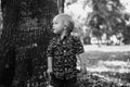 Precious Little Toddler Boy Dressed Up in the Outdoors Forest Park for Portraits in Autumn by Big Natural Tree Having Excited Fun Royalty Free Stock Photo