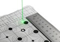 Precise measurement setup with ruler and grid paper featuring green laser pointer aiming at a marked point Royalty Free Stock Photo