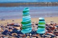 Precisely balanced pyramids of glass stones from broken bottles polished by the sea against the backdrop of the sea Royalty Free Stock Photo