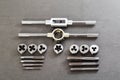 Precision metalworking tap and die set including tap wrenches and various thread cutting tools displayed on dark gray surface for Royalty Free Stock Photo
