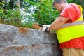 With precision and skill construction worker attached concrete block securely to retaining wall.