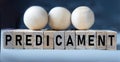 PREDICAMENT - word on wooden cubes on a blue background with wooden round balls