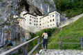predjama castle built into a mountain in the nature near to postojna cave with a tourist woman watching it