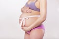 Pregnan woman in underwear cherish her belly with ribbon on it.