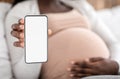 Pregnancy App. Black pregnant lady demonstrating smartphone with blank white screen