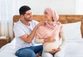 Pregnancy body massage. Caring muslim husband massaging shoulders of his young happy pregnant wife