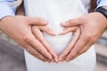 Pregnancy concept - couple making a heart shape with their hands on the pregnant belly. Hands of family members holding a belly Royalty Free Stock Photo