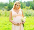 Pregnancy concept - pregnant woman with chamomiles flowers on belly over sunny summer Royalty Free Stock Photo