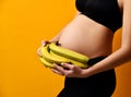 Pregnancy concept. Pregnant woman hold banana near abdomen on yellow Royalty Free Stock Photo