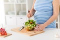 Close up of pregnant woman cooking salad at home Royalty Free Stock Photo