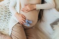 Pregnancy. Cropped photo of pregnant woman holding pair of cute blue baby socks on belly Royalty Free Stock Photo