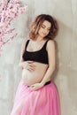 Pregnancy fitness and sport concept happy pregnant woman near the pink sakura tree. ballet dancer on gray background Royalty Free Stock Photo