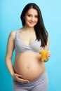 Young undressed pregnant woman with big tummy holding a glass of juice