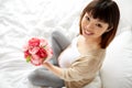 Happy asian pregnant woman with flowers in bed Royalty Free Stock Photo