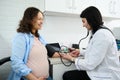 Pregnancy-induced hypertension. Prophylaxis of eclampsia. Obstetrician doctor measures blood pressure of pregnant woman Royalty Free Stock Photo