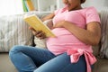 Happy pregnant african woman reading book at home Royalty Free Stock Photo