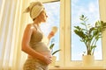 Pregnant young woman with bath towel on head with cup of tea looking out window Royalty Free Stock Photo