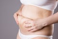 Pregnancy line - linea nigra, tummy tuck, overweight female body and flabby belly on gray background