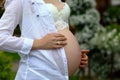 Pregnancy, love, people and expectation concept - close up of pregnant woman belly over green natural background