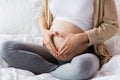 Happy pregnant woman making heart gesture in bed Royalty Free Stock Photo