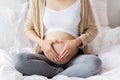 Happy pregnant woman making heart gesture in bed Royalty Free Stock Photo