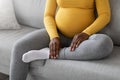 Cropped of black pregnant woman sitting on couch at home