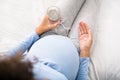 Pregnancy medicines. Expectant woman holding pill and glass of water Royalty Free Stock Photo