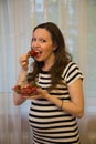 Pregnancy, motherhood, the concept of waiting-close - up of a happy pregnant woman with a big belly in a window with strawberries Royalty Free Stock Photo