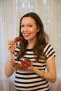 Pregnancy, motherhood, the concept of waiting-close - up of a happy pregnant woman with a big belly in a window with strawberries Royalty Free Stock Photo