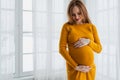Pregnancy motherhood people expectation future. Pregnant woman with big belly standing near window at home. Girl hugging Royalty Free Stock Photo