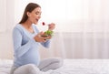 Pregnant Girl Eating Vegetable Salad Sitting On Bed In Bedroom Royalty Free Stock Photo