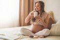 Pregnancy and nutrition. Pregnant woman enjoying donuts and tea in bed, free space. Concept of expectation and health