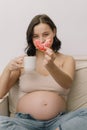 Pregnancy and nutrition. Pregnant woman enjoying donuts and tea.