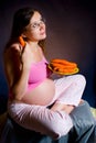 Pregnancy and nutrition - pregnant woman with ripe carrot. cute pregnant girl with a dreamy look.