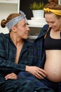 pregnancy and people concept - happy man hugging his pregnant wife sitting at home on the couch. Royalty Free Stock Photo