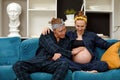 pregnancy and people concept - happy man hugging his pregnant wife sitting at home on the couch. Royalty Free Stock Photo