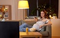 Pregnant woman with remote control watching tv Royalty Free Stock Photo